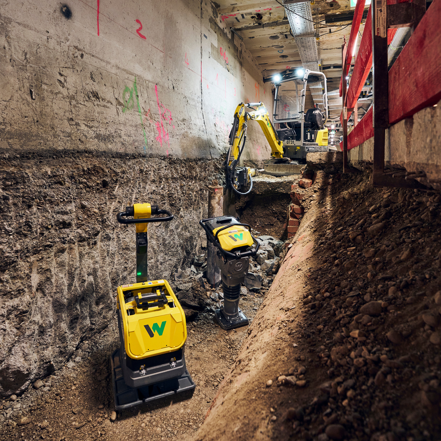 yellow vibratory plate, yellow rammer and yellow excavator at construction site at Munich main train station